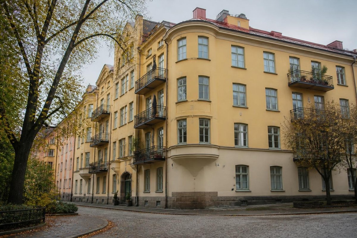 Gult sekelskiftshus med balkonger vid en kullerstensgata i en svensk stad